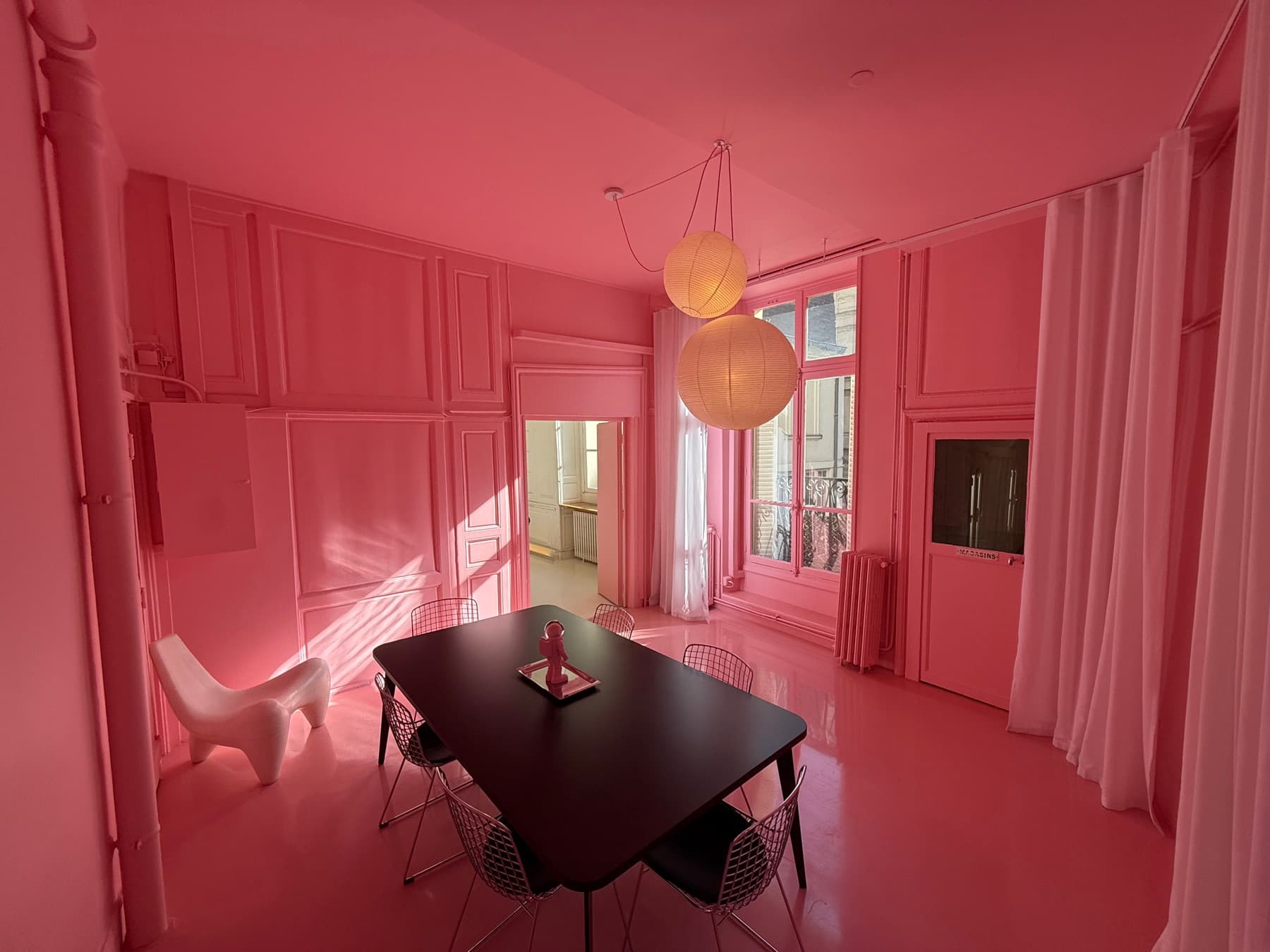 Pink room with black table, Bertoia chairs and globe pendant lights — natural light, painted mouldings