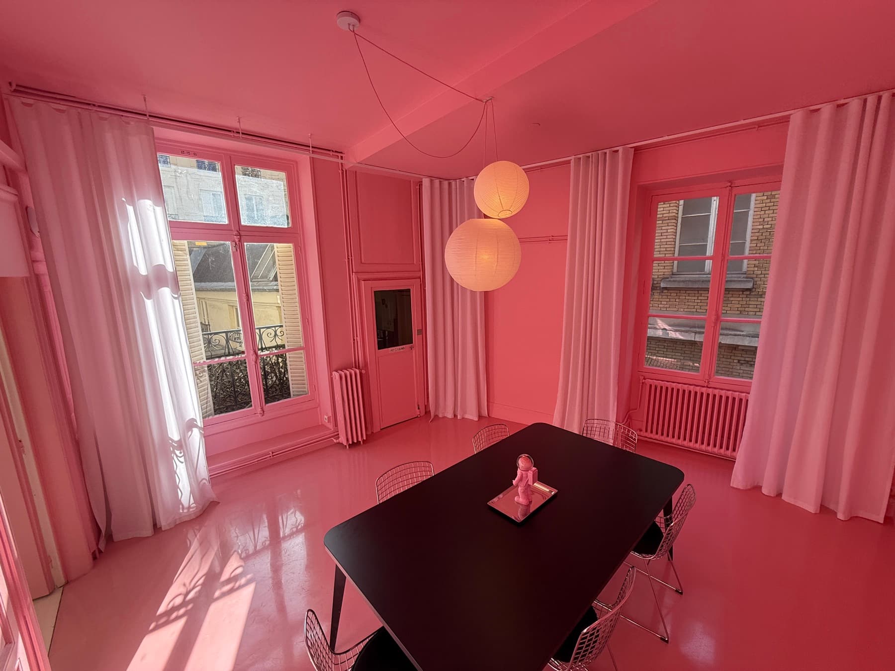 Pink room window side with round pendant lights and designer table — The Pink Apartment Paris