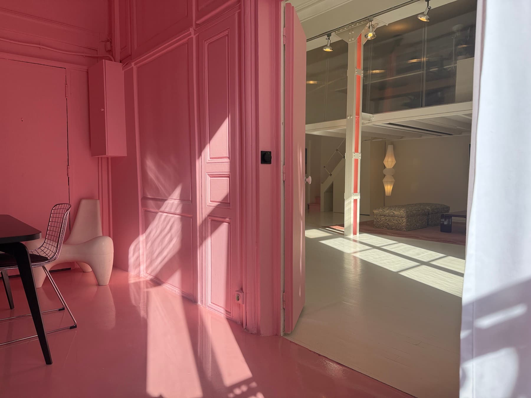 Transition between the pink room and the main space — designer chair and natural light