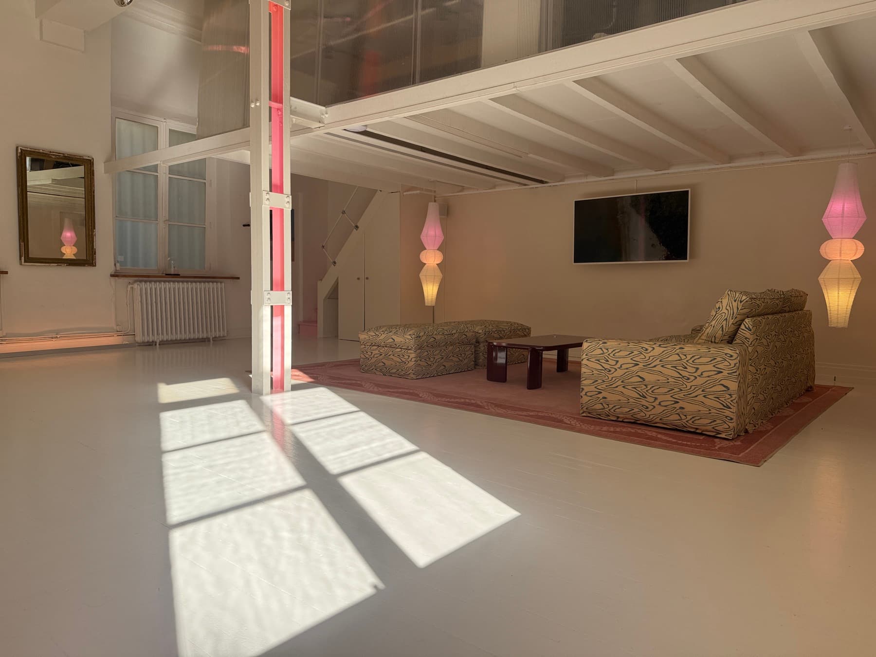 Main lounge with patterned sofas, designer lamps, TV screen and white beams