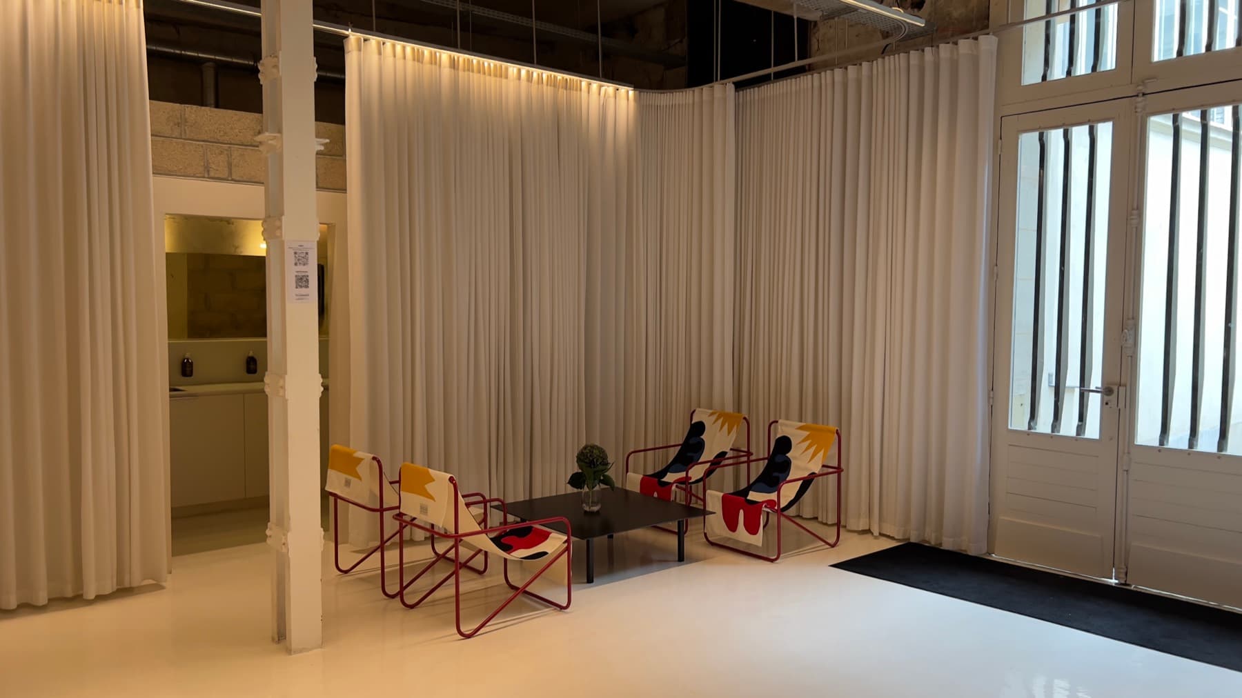 Entrance with workshop glass wall, designer armchairs and kitchenette — Chez Les Plombiers