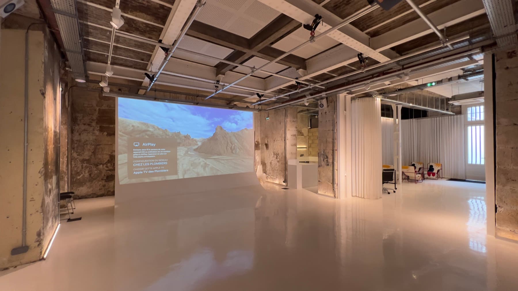 Panoramic view of the 200 m² main hall with pink sofa and video projection — Chez Les Plombiers