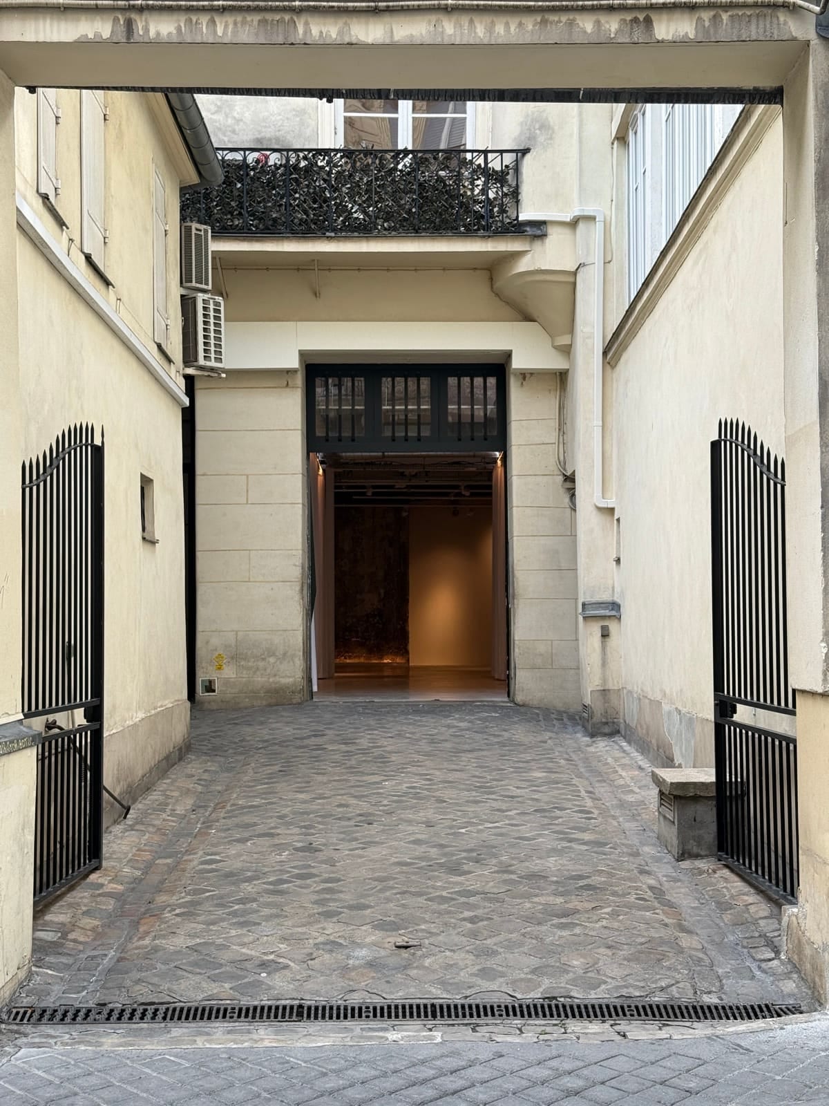 La cour pavée, avec l'entrée de L'Atelier ouverte au fond