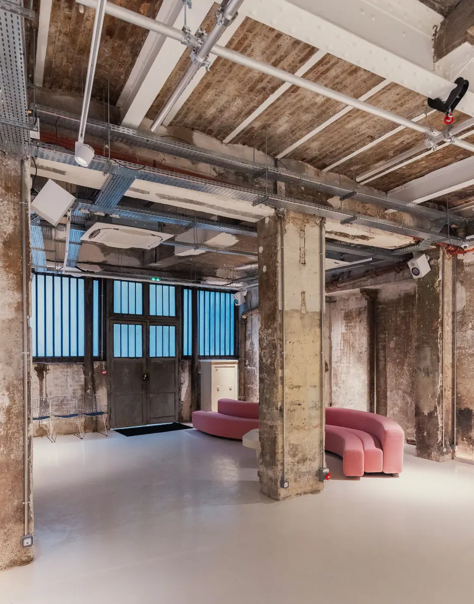 L'Atelier, ses poteaux bruts et ses canapés roses, vu depuis le fond de la salle